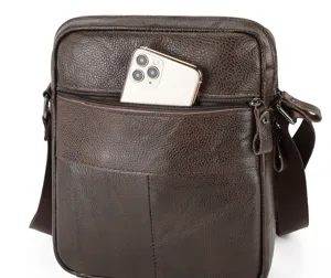 Close-up detail of men's leather shoulder bag showing front zipper pocket and phone holder.
