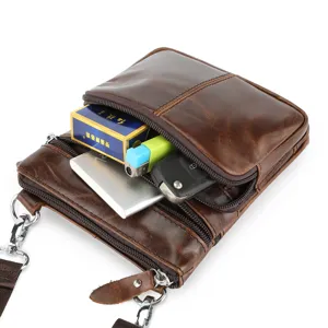 Detailed view of brown leather men crossbody bag front pocket capacity with durable metal hardware.
