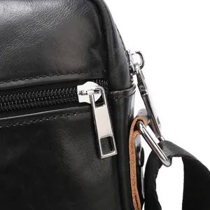 Close-up view of black leather men's messenger bag zipper detail, premium casual style.