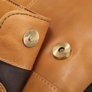 Premium cowhide leather bag magnetic snap button hardware detail closeup photo.