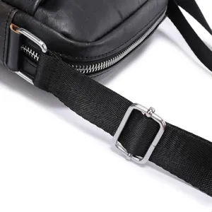 Close-up detail of black leather men shoulder bag strap, metal buckle and zipper hardware.