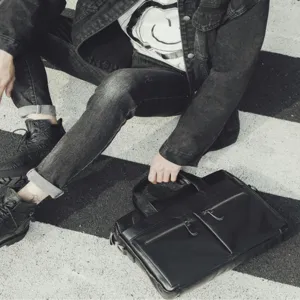 Black genuine leather business briefcase with dual zip pockets and stylish handle for men.