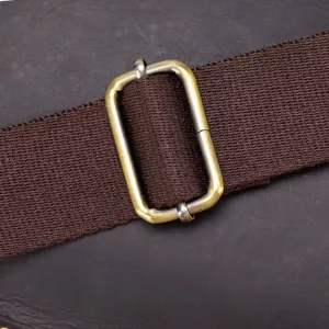 Close-up of durable brown canvas shoulder bag strap with adjustable metal brass buckle hardware.