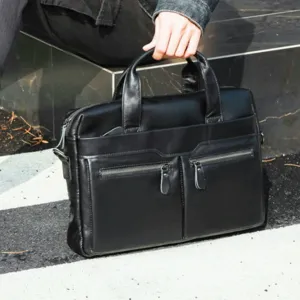 Detail shot of black leather business briefcase with front zippered pockets and sturdy handles.