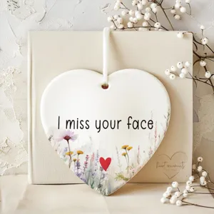 Close-up detail of heart-shaped ceramic hanging ornament with floral design and sweet message.