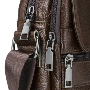 Close-up detail of mens brown leather shoulder bag featuring durable metal zippers and hardware.