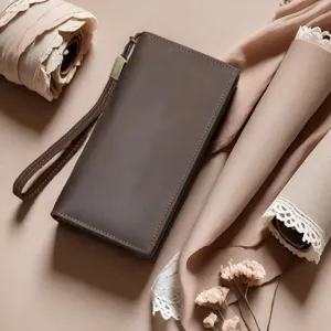 Close-up detail shot of a brown crazy horse leather men long wallet with wrist strap and zipper.