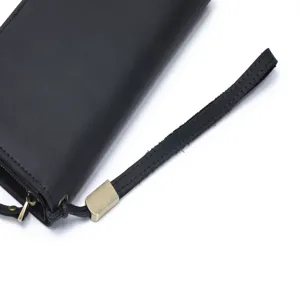 Close-up detail of black leather men's long wallet with wrist strap and metal zipper.