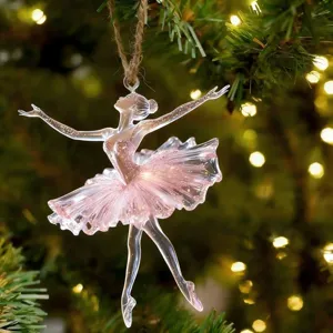 Gros plan d'un ornement de ballerine en acrylique rose transparent, pose gracieuse sur l'arbre.