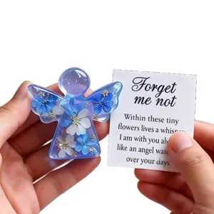 Close-up detail of the resin angel keepsake with blue dried forget-me-not flowers inside.
