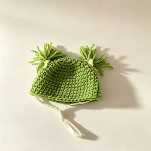 Handcrafted green crochet baby hat with cute pigtail tassels and soft chin straps for kids.