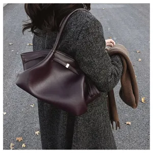 Λεπτομερής λήψη της χαλαρής μπορντό δερμάτινης τσάντας tote με μεταλλικό κούμπωμα.