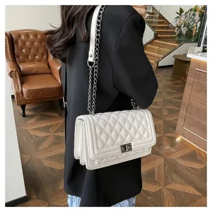 Detailed shot of a stylish white quilted chain shoulder bag worn on model, elegant style.