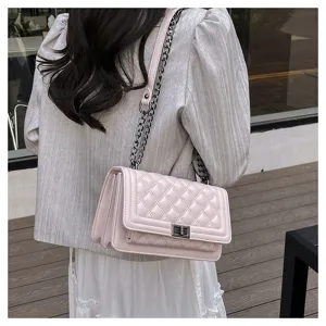 Detail view of a chic pink quilted crossbody bag with stylish metallic chain strap and lock.