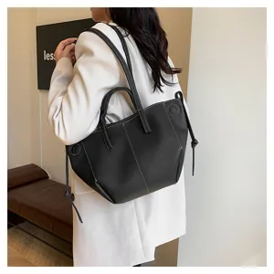 Women stylish black leather tote bag with contrast stitching, versatile shoulder handbag.