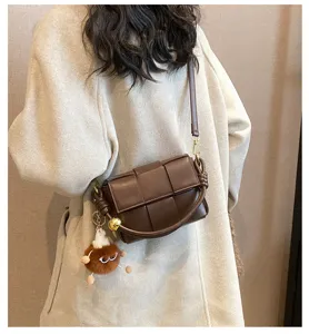 Stylish brown woven leather crossbody bag with knot handle and cute plush charm pendant.