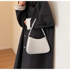 Close-up detail of silver underarm baguette shoulder bag, sleek minimalist design.