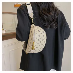 Detail view of a beige crescent sling bag with cute bear pattern, adjustable wide strap.