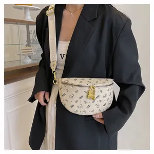 Detail view of stylish cream fanny pack with cute bear print, gold chain and zipper closure.
