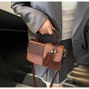 Detailed shot of retro color-block handbag with textured fabric and leather splicing design.