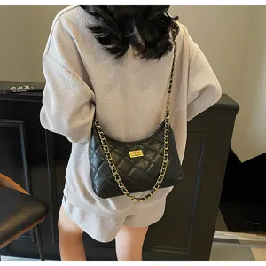 Detail view of women's black quilted shoulder bag with gold chain strap and stylish design.