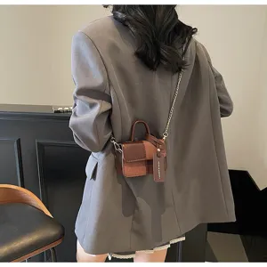 Detail view of the small color-blocked retro crossbody bag with chain strap and handle.
