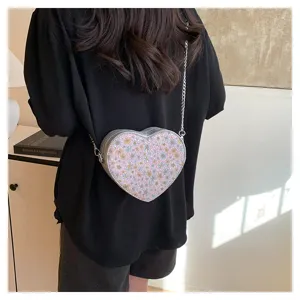 Detail shot of a stylish heart-shaped floral crossbody bag with a metallic chain strap.