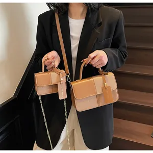 Detailed closeup view of the stylish contrast color mini square handbag with chain strap.