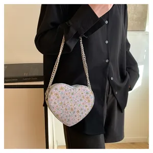 Detail view of a cute floral heart-shaped shoulder bag with metallic chain strap.