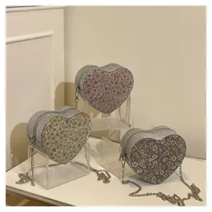 Detail view of sparkly floral heart-shaped crossbody bag with metal chain strap and fine zipper.