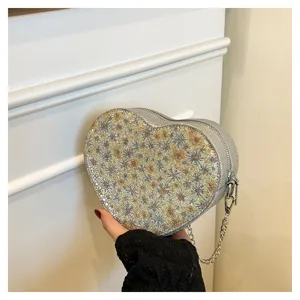 Close-up view of the sparkling heart-shaped women bag with chic floral pattern and silver chain.