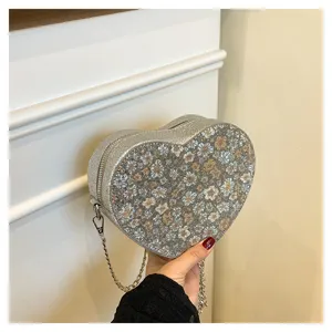 Heart-shaped glitter chain bag detail view, showing delicate floral pattern and sparkling surface.