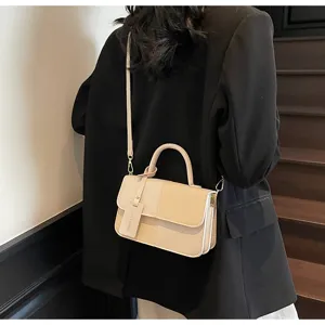 Detail view of the chic two-tone retro crossbody bag with top handle and stylish charm.