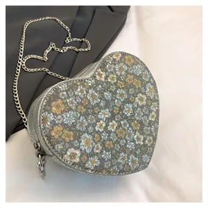 Heart-shaped floral chain crossbody bag with sparkling glitter texture and strap.
