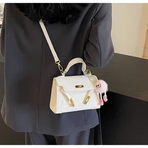 Detail view of white embossed women handbag, PU leather shoulder bag with gold hardware.