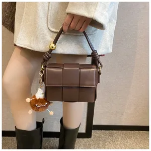 Chic dark brown woven leather handbag with knotted handle and cute plush charm for women.
