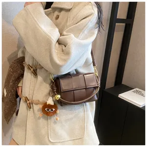 Woven leather shoulder bag for women, stylish crossbody handbag with plush charm.
