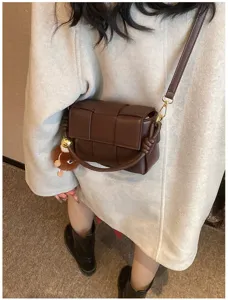 Dark brown woven shoulder bag with chic padded design and cute plush pendant details.