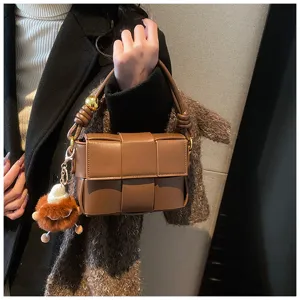 Brown woven leather shoulder bag for women, stylish crossbody handbag with cute fluffy plush charm.