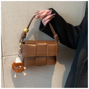 Brown woven shoulder bag detail, stylish PU leather handbag with plush charm pendant.