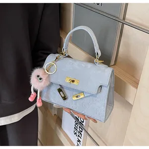 Light blue stylish Kelly style handbag with cute plush charm and gold hardware detail.