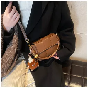 Stylish brown woven crossbody bag with cute plush charm, perfect for winter daily fashion wear.