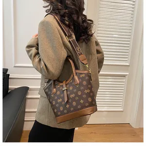 Detail view of a vintage brown monogram bucket bag, showing leather trim and wide shoulder strap.