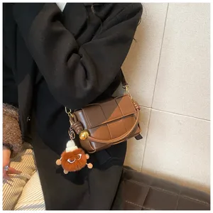 Brown woven leather shoulder bag with plush charm, stylish crossbody purse for women