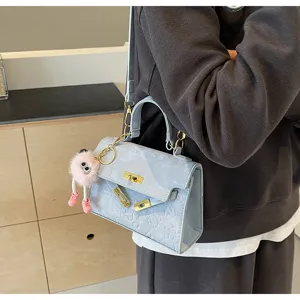 Light blue embossed Kelly handbag with chic metal lock hardware and cute fluffy pink monster charm.