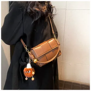 Brown woven leather shoulder bag with plush charm, trendy crossbody handbag for women.