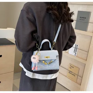 Detail view of light blue embossed Kelly shoulder bag with cute plush pendant for women.