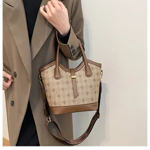 Detailed view of women retro bucket bag, monogram canvas with brown leather trim handle.