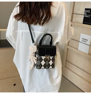 Details of the stylish black and white plaid crossbody phone bag with cute bunny pendant.