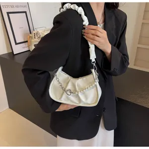 Close-up of white pleated shoulder bag with pearl chain strap, stylish modern fashion accessory.